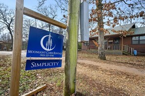 A wooden signboard with a logo and the name 'Moonlight Cabin Rentals' along with a contact number.