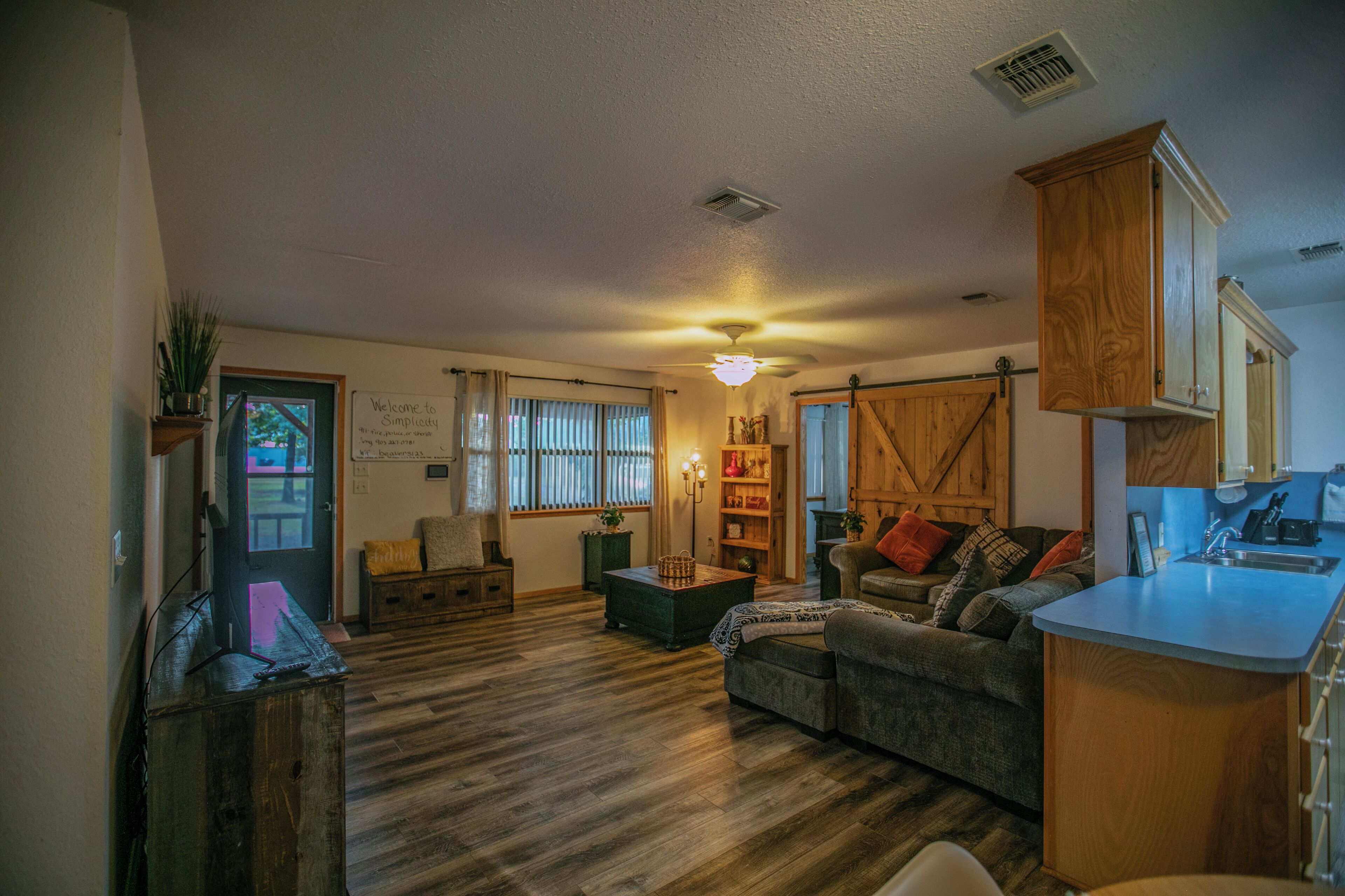 A cozy living room with a fireplace, a dining area with a kitchen counter, and a large wooden door.