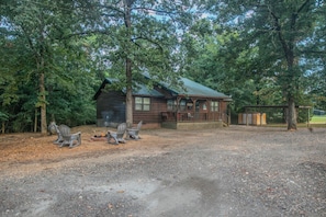A rustic cabin with a porch, surrounded by trees.