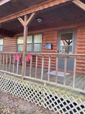 A wooden cabin with a covered porch, windows, and a mailbox.
