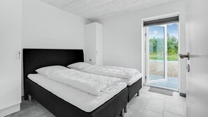 Ein Schlafzimmer mit zwei Betten, einer weißen Tür zu einem Außenbereich und einer Decke mit Gittermuster.
