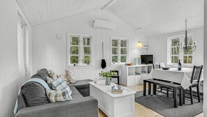 Un salon moderne avec un canapé gris, une table basse blanche et un coin repas comprenant une table et des chaises.