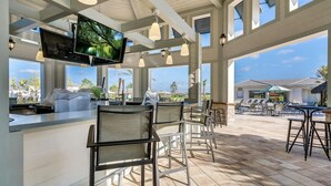 A spacious outdoor area with a bar, seating, and a TV screen.
