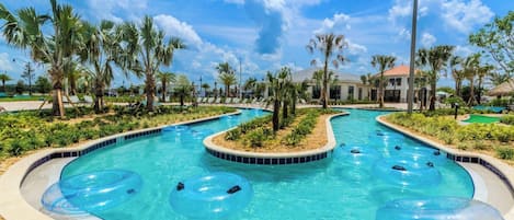 Una piscina con múltiples toboganes acuáticos y flotadores inflables, rodeada de palmeras y un cielo despejado.
