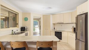 A modern kitchen with a central island, stainless steel appliances, and light-colored cabinetry.