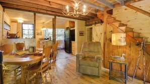 A wooden interior with a dining table, chairs, a sofa, a lamp, and a staircase. - Adirondacks Cabin w/ Fire Pit on Otter Lake! (Forestport)