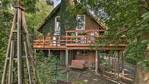 Ein Holzhaus mit Balkon, umgeben von Grün und einem Garten.