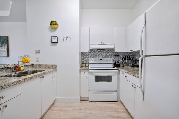Effortlessly cook and entertain in this well-equipped kitchen with a stove, refrigerator, and sink.