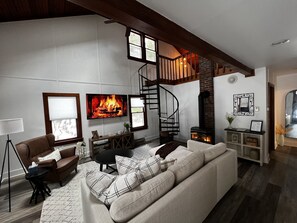 A cozy living room with a fireplace, a sofa, a coffee table, and a TV. - 3BR Poconos Cottage • Near Kalahari, Jack Frost, Golf & Shops!  (Pocono Pines)
