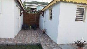 Ein kleiner, umzäunter Patio-Bereich mit gefliestem Boden, einem Holzzaun und einem kleinen Tisch mit Stühlen.