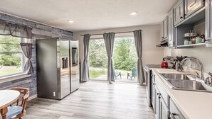 A modern kitchen with a built-in refrigerator, a sink, and a dining area with a table and chairs. - Cozy Adirondack Loft Near Lake Champlain & George, Hiking and Historical Sites (Ticonderoga)