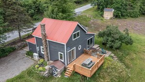 A two-story house with a red roof, a wooden deck, and a stone chimney. - Cozy Adirondack Loft Near Lake Champlain & George, Hiking and Historical Sites (Ticonderoga)