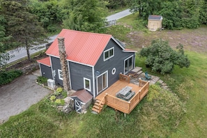 A two-story house with a red roof, a wooden deck, and a stone chimney.