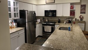 A modern kitchen with white cabinets, stainless steel appliances, granite countertops, and a granite backsplash. - Winterplace Condo Steps away from slopes (Ludlow)