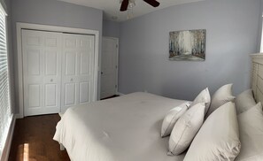 Ein Schlafzimmer mit einem großen Bett, einem Deckenventilator und einer Tür.