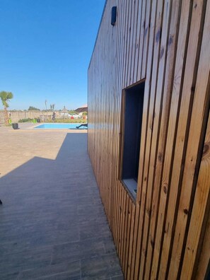 Ein Holzgebäude mit einem Fenster und einem Pool im Hintergrund.