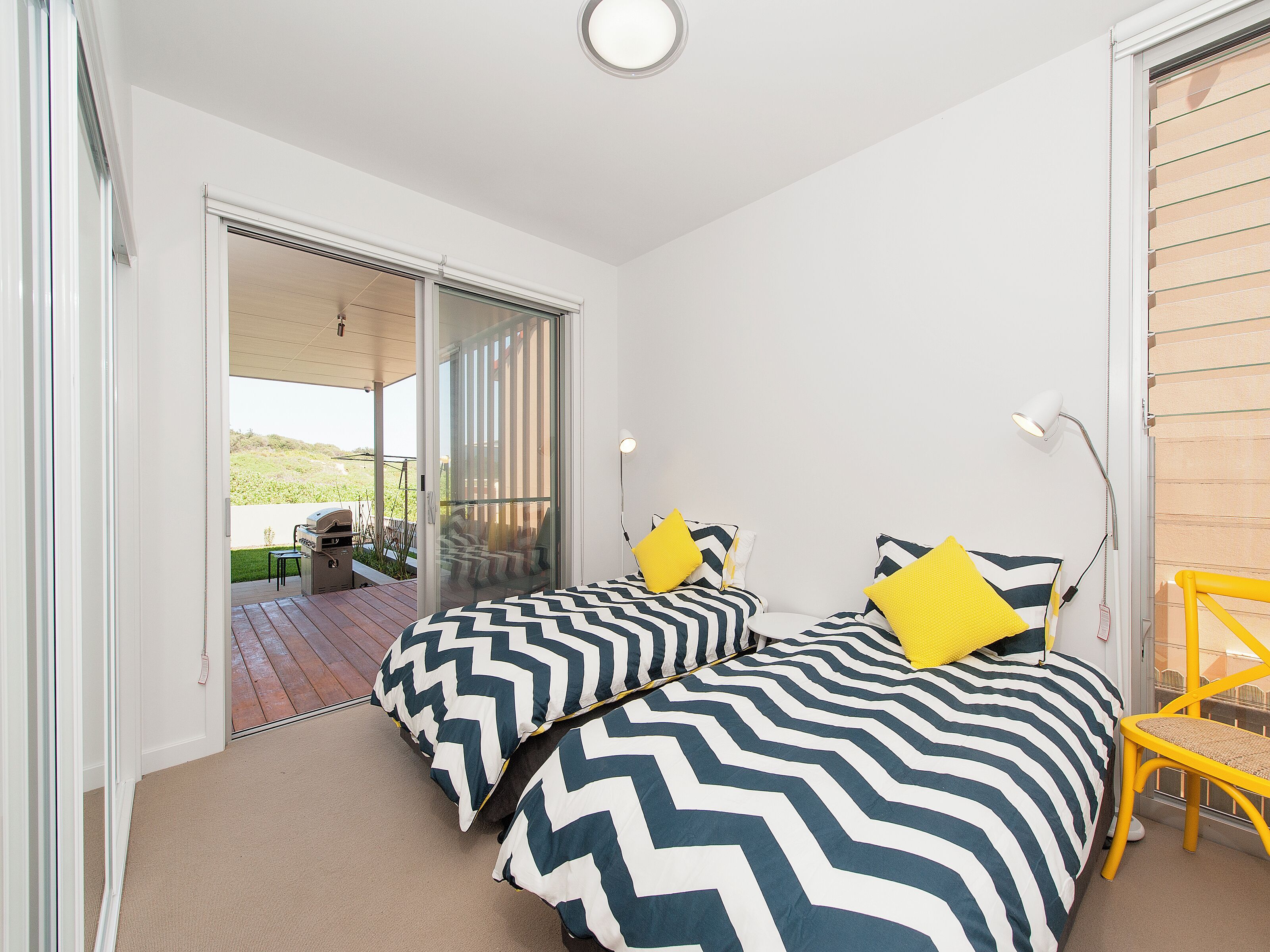 Bright twin bedroom with private deck access and outdoor grill