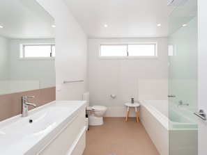 A modern bathroom with a large bathtub, a separate toilet, and a small sink. - 41A Ocean Avenue - reserve front Ocean Views (Anna Bay)