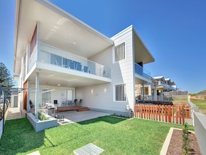 A modern two-story house with a balcony, a covered patio, and a well-maintained lawn. - 41A Ocean Avenue - reserve front Ocean Views (Anna Bay)