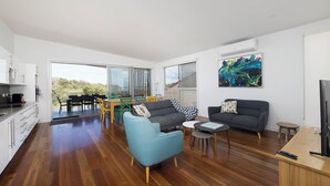 A modern living space with a dining area, two sofas, a coffee table, and a kitchen area.
