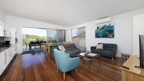 A modern living space with a dining area, two sofas, a coffee table, and a kitchen area.