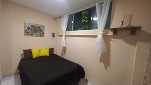 A bedroom with a bed, a window with curtains, a wall-mounted shelf, and a painting.