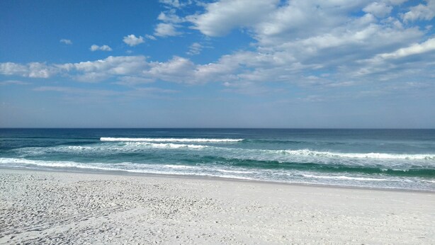 A beach with waves and a clear sky.
