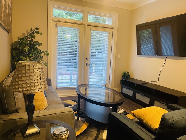 Relax in this stylish living room with a comfortable sofa, flat-screen TV, and sliding glass door to an outdoor area.