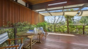 An outdoor wooden deck with a table and chairs, surrounded by greenery and a wooden fence. - HAILEY@KURRAJONG - stylish and delightful. SPECIALS ON NOW ! (Kurrajong)
