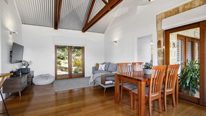 A spacious living area with a wooden dining table, a sofa, and a TV mounted on the wall. - HAILEY@KURRAJONG - stylish and delightful. SPECIALS ON NOW ! (Kurrajong)