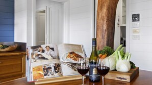 A kitchen with a wooden table displaying a wine bottle, two glasses of wine, a cookbook, and fresh vegetables. - HAILEY@KURRAJONG - stylish and delightful. SPECIALS ON NOW ! (Kurrajong)