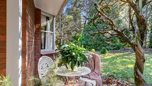 A patio with a white table and chairs, a potted plant, and a brick wall.