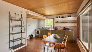 Uma cozinha moderna com armários de madeira, uma ilha central e um espaço de jantar com mesa e cadeiras.