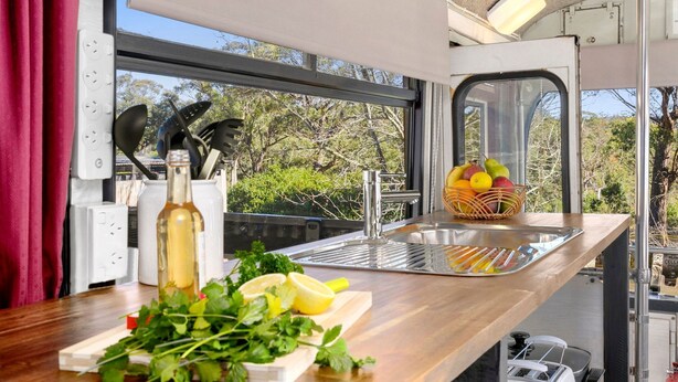 Una cocina con encimera de madera, un fregadero y una ventana con vistas a un paisaje natural.