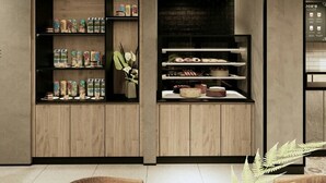 A modern interior with wooden panel walls, shelves displaying various products, and a seating area with a table and chairs. - Fieris Hotel Rawamangun (Jakarta)