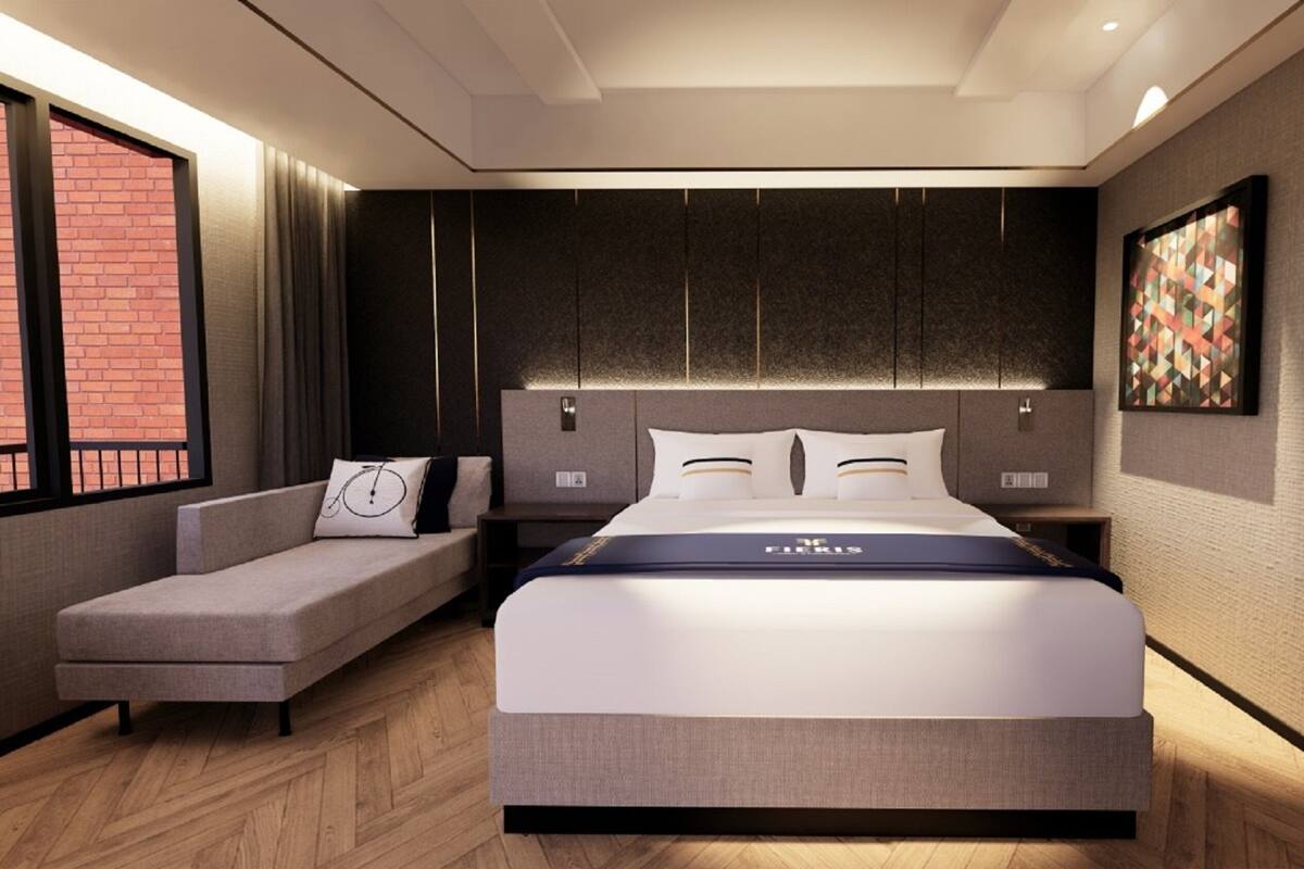 Een moderne hotelkamer met een groot bed, een zithoek en uitzicht op een bakstenen gebouw.
