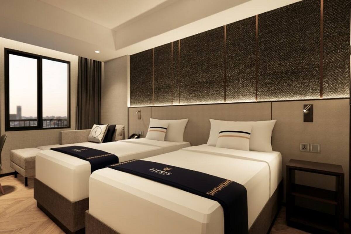 Een hotelkamer met twee bedden, een bureau en een stoel.