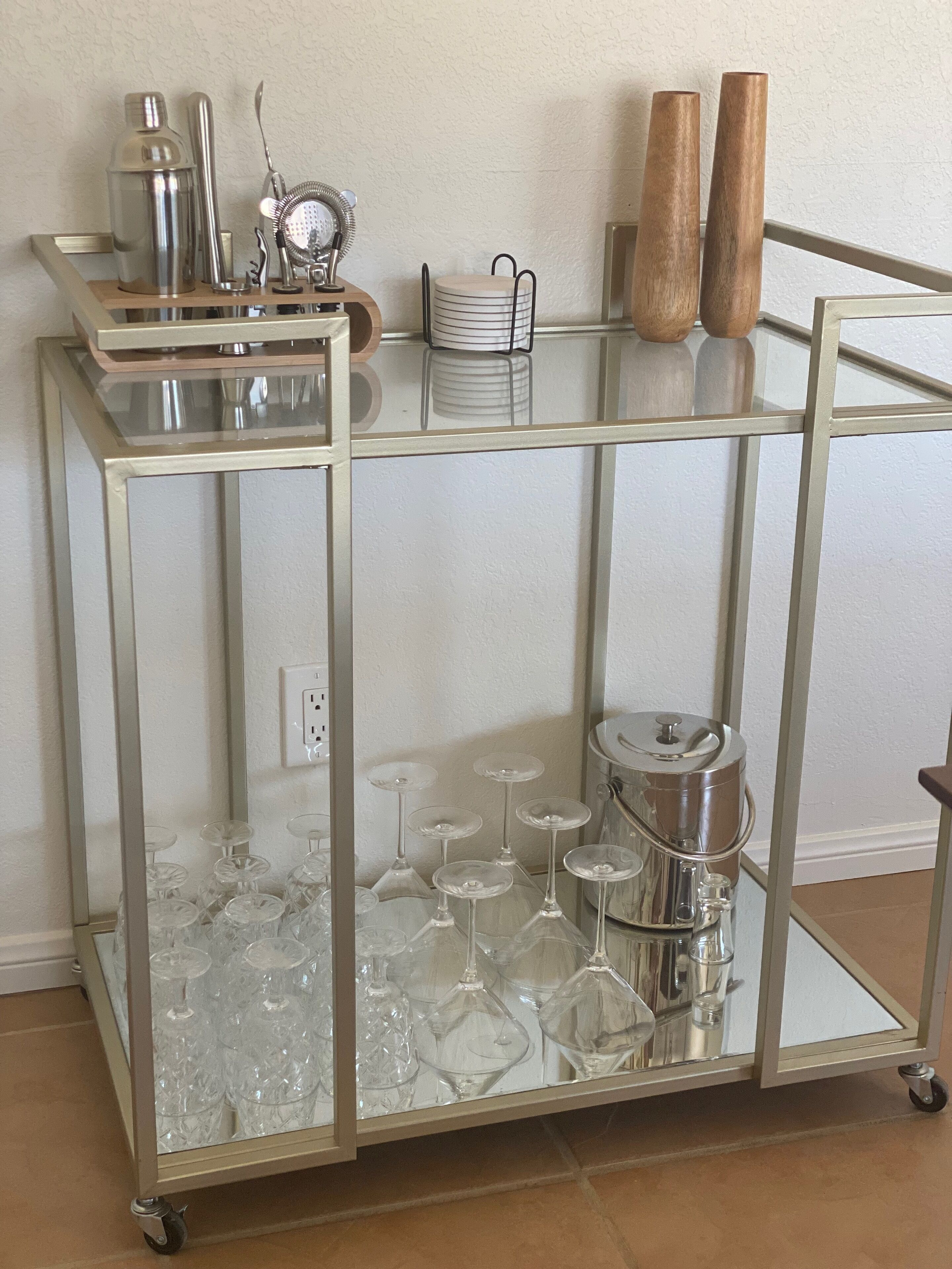 A glass-fronted cart with wine glasses and a coffee pot.