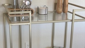 Un chariot à façade vitrée contenant des verres à vin et une cafetière.