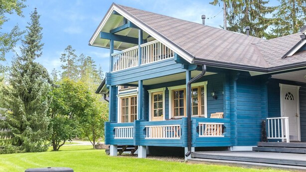 Une maison à deux étages dotée d’un balcon, d’un porche et d’une pelouse bien entretenue.