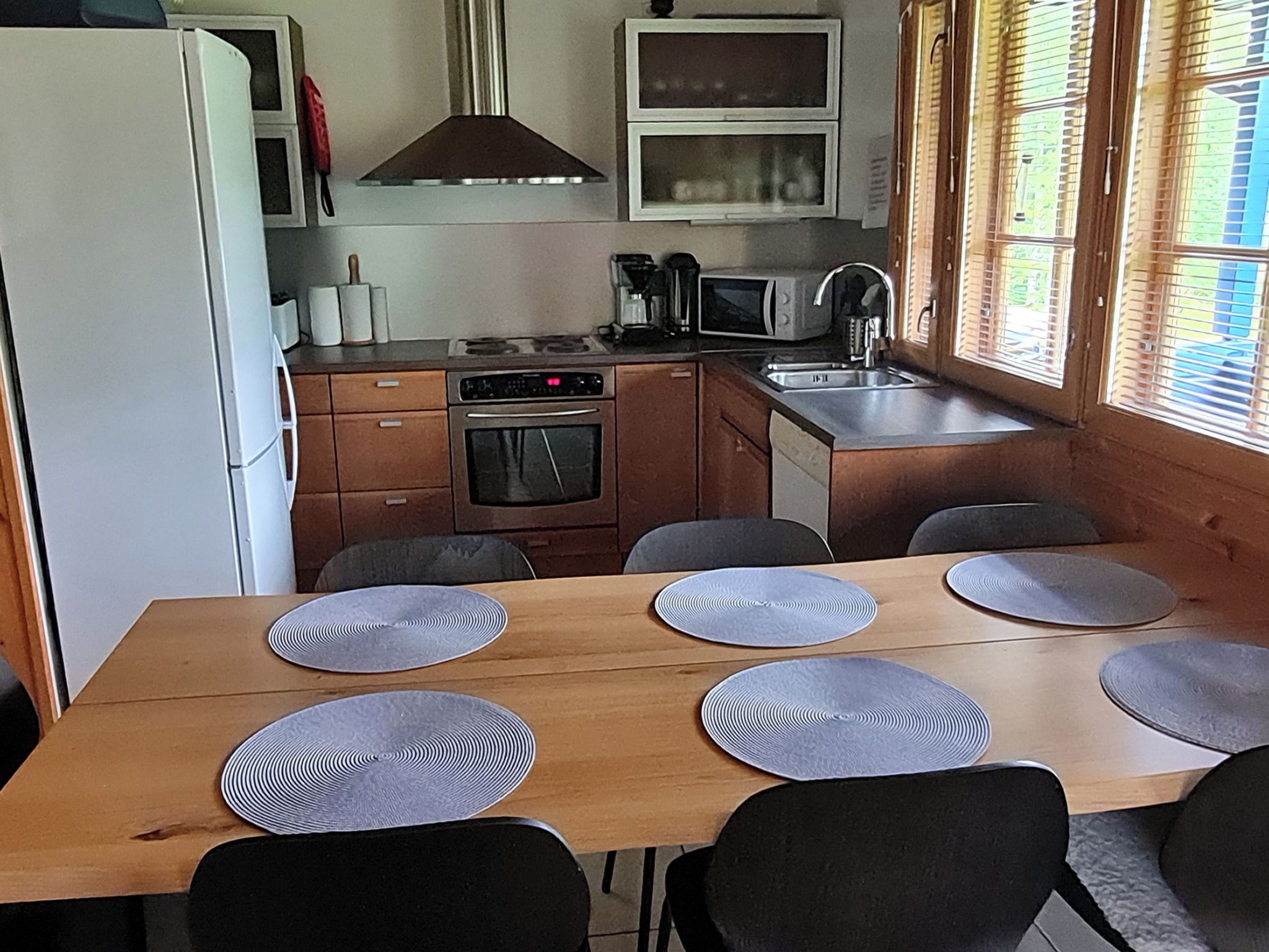 A compact kitchen with a microwave, stove, and sink, and a dining area with a table and chairs.