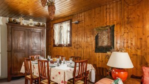 Un coin repas avec une table en bois dressée pour quatre personnes, entourée de chaises en bois.