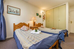 A room with two beds, a nightstand with a lamp, a painting on the wall, and a wardrobe. - Apt L'Outa 111 Mont Blanc View in Chamonix center for 6, Chamonix, France (Chamonix)