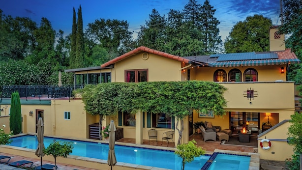 A two-story house with a swimming pool, outdoor seating, and a covered patio area.