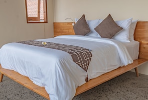 A bed with a wooden frame, white bedding, and a brown patterned throw.