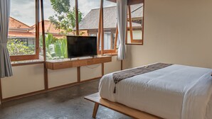 A bedroom with a bed, a TV mounted on a window, and a view of the outside. - Villa Avyathi at Anandathu Villas - Tropical 2BR Contemporary Villa in Canggu (Bali)