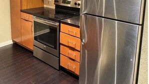 Une cuisine avec des meubles en bois, un réfrigérateur en acier inoxydable, un four à micro-ondes et un four traditionnel.