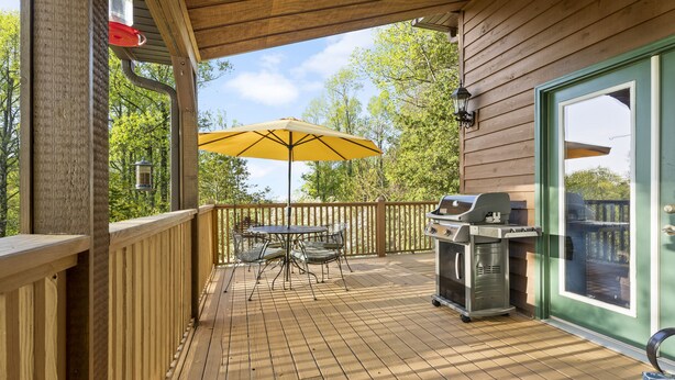 A wooden deck with a table and chairs, a grill, and a yellow umbrella. - Sky Dog Pet Friendly Home Dupont Brevard Hiking Mountain Biking Porch Waterfalls (Brevard)