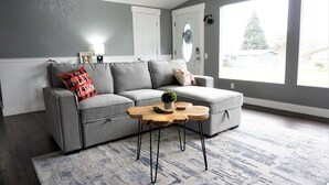 Un salon moderne avec un canapé gris, une table basse en bois et un tapis gris.