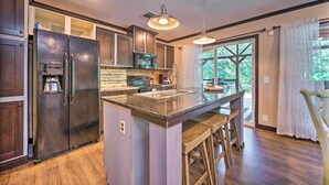 A kitchen with a large island, dark wooden cabinets, stainless steel appliances, and a window with a view of greenery. - Pet-Friendly Home w/ Deck in Broken Bow! (Broken Bow)